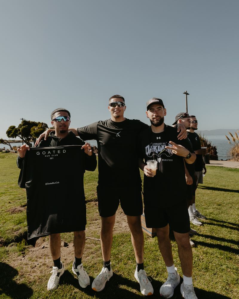 Runners holding up a Goated Run Club shirt
